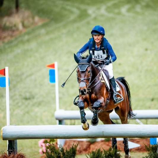 An equestrian jumping a fence on a horse wearing a Hit Air system.