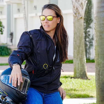 Woman in a Hit Air HDS black jacket holding a motorcycle helmet outdoors.