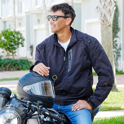 Man wearing a Hit Air HDS jacket in black sitting on a motorcycle with a helmet.