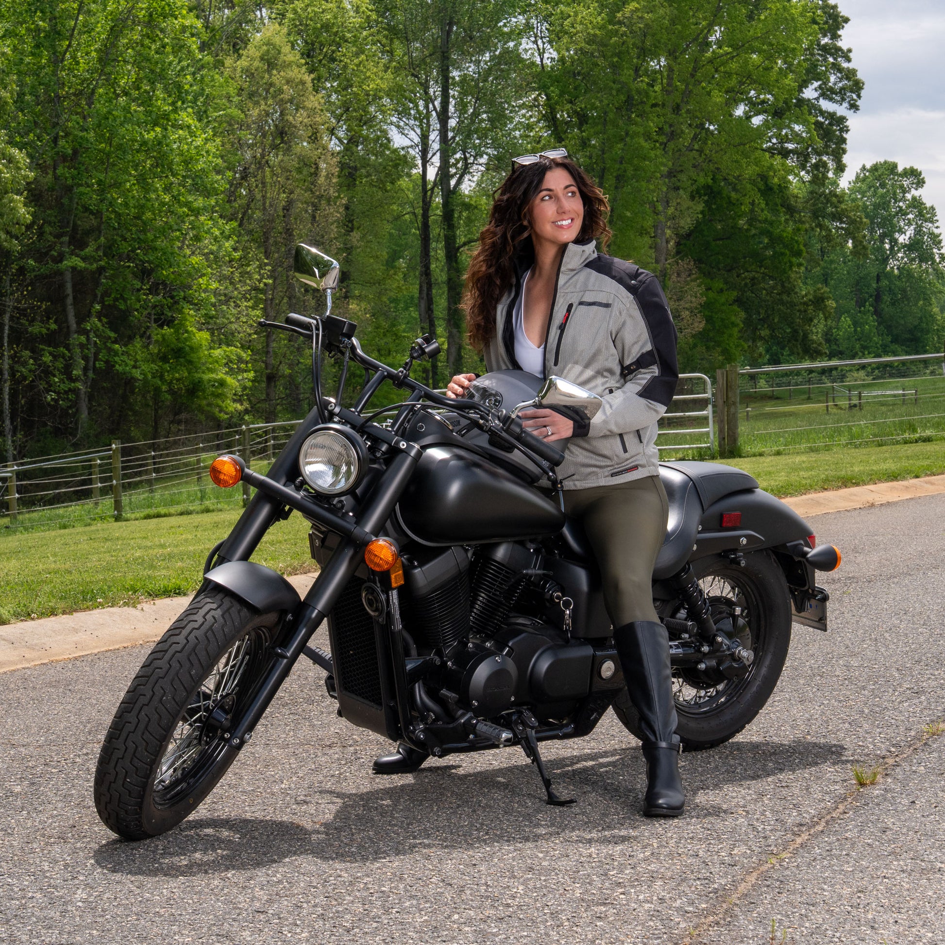 Woman sitting on a motorcycle in a grey mesh HDS jacket.