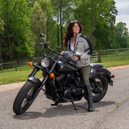 Woman sitting on a motorcycle in a grey mesh HDS jacket.