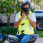 Person wearing a helmet and high-visibility vest sitting on a motorcycle.