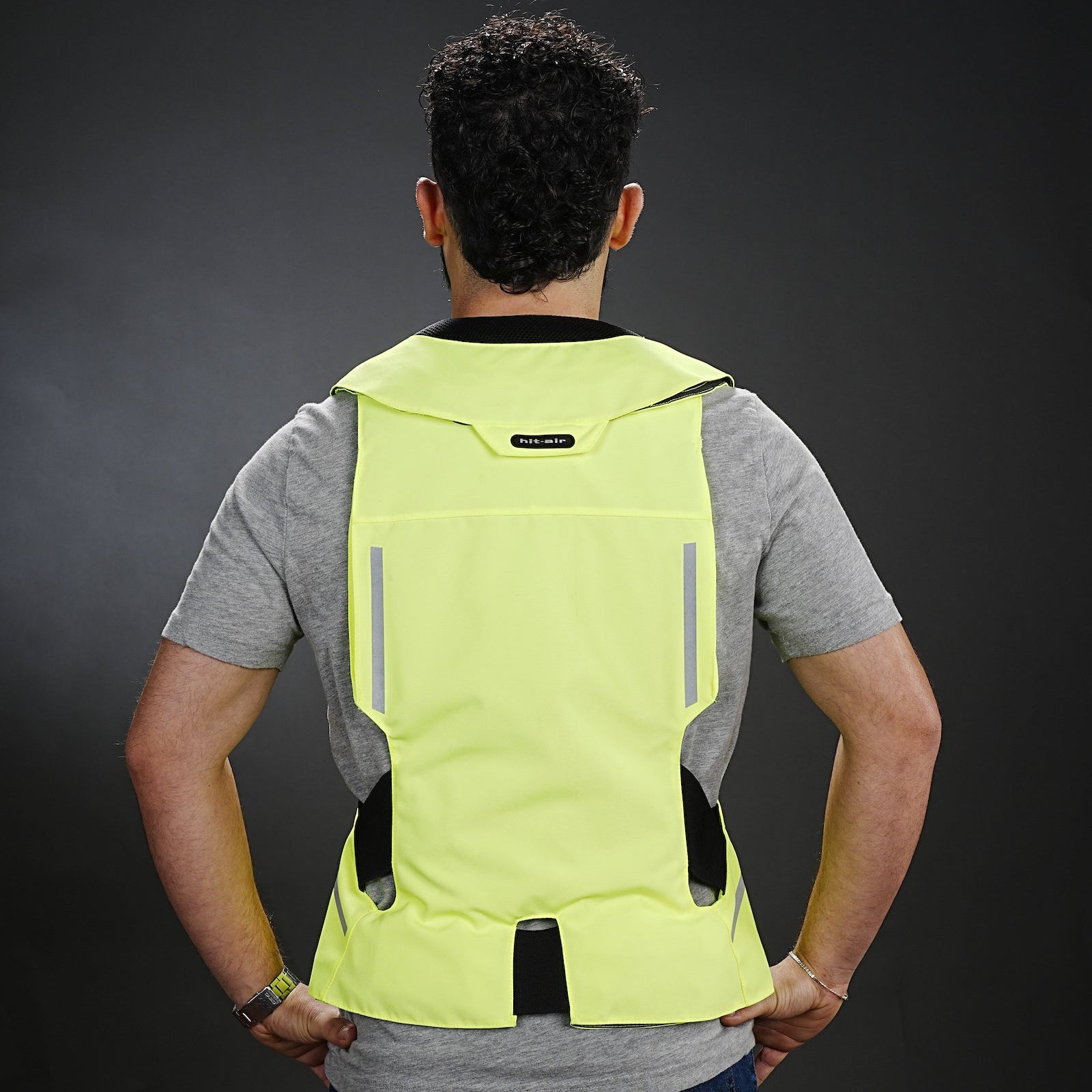 Person wearing a bright yellow ST Hit Air safety vest on a dark background