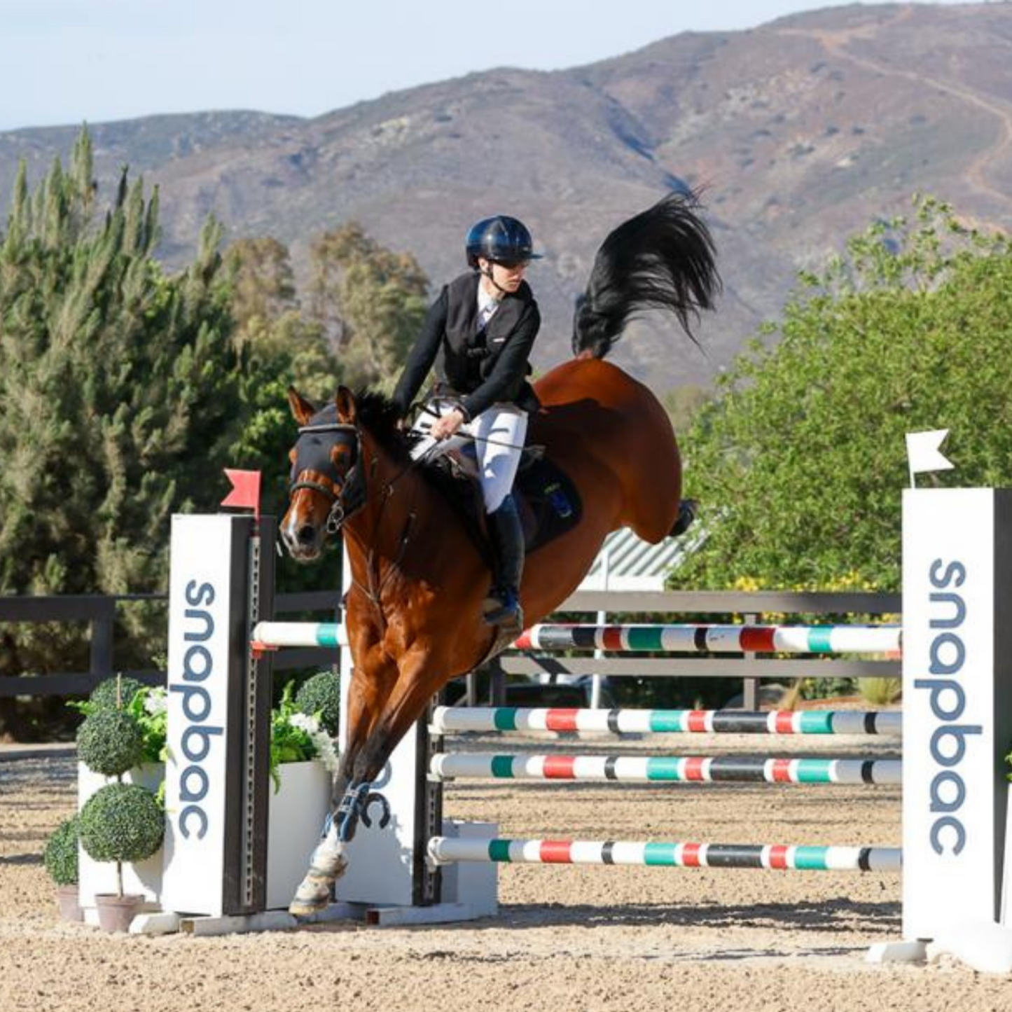 A english show jump horse rider jumping a fence wearing a Hit Air vest.