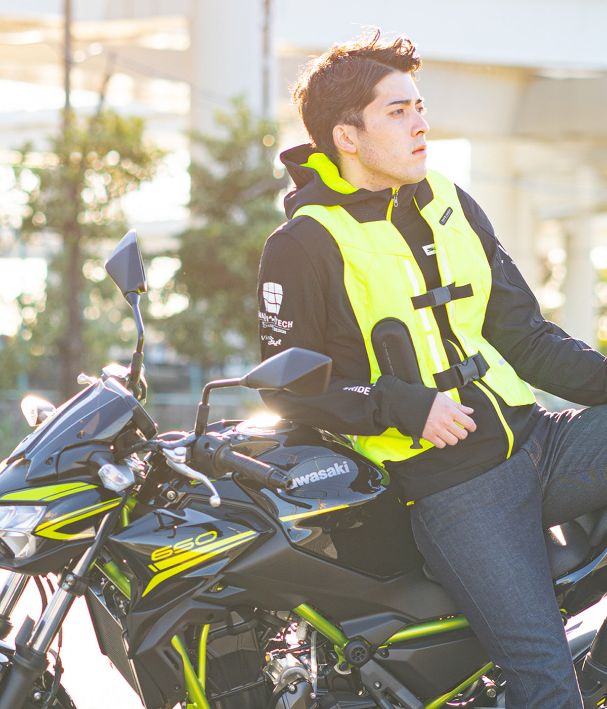 Person wearing a high-visibility vest sitting on a motorcycle with a blurred background